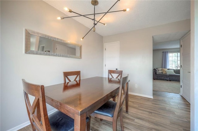 2406 Alabama St Unit 9D, Lawrence, KS 66046 - dining space featuring a chandelier, light wood-style flooring, and a textured ceiling