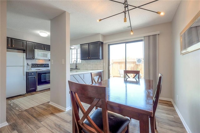 2406 Alabama St Unit 9D, Lawrence, KS 66046 - dining space with light wood-style flooring, a textured ceiling, and a chandelier
