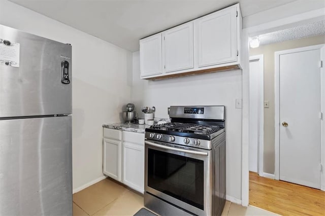 8700 Independence Ave, Kansas City, MO 64125 - kitchen featuring stainless steel appliances, white cabinets, light tile patterned floors, and baseboards