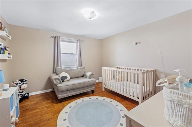 8700 Independence Ave, Kansas City, MO 64125 - bedroom with wood finished floors, baseboards, and a crib