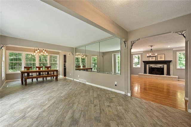 8 Apache Dr, Lake Winnebago, MO 64034 - living room with a chandelier, wood finished floors, baseboards, a textured ceiling, and a brick fireplace