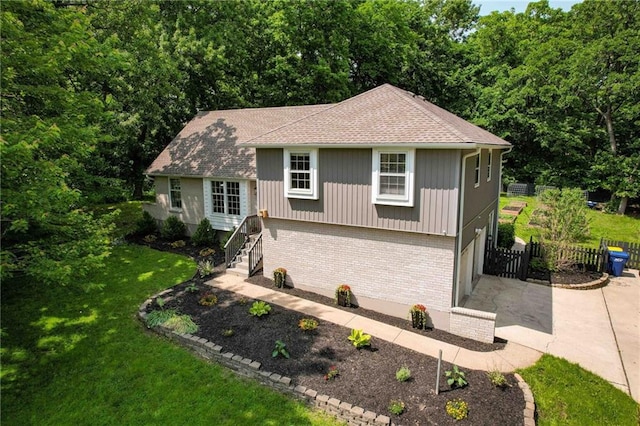 8 Apache Dr, Lake Winnebago, MO 64034 - view of front of property with brick siding, concrete driveway, an attached garage, roof with shingles, and a wooded view