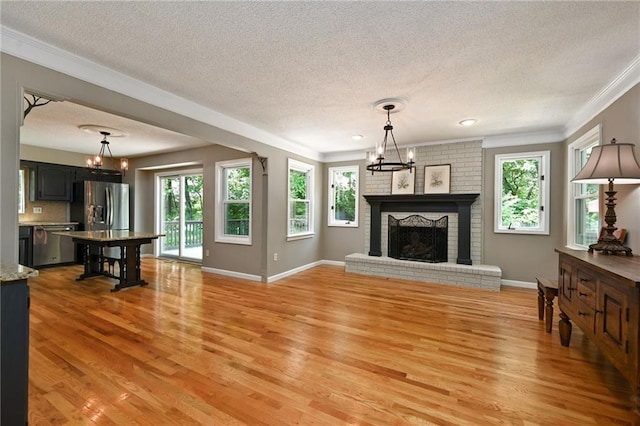 8 Apache Dr, Lake Winnebago, MO 64034 - living room with a chandelier, a textured ceiling, light wood-type flooring, crown molding, and a brick fireplace