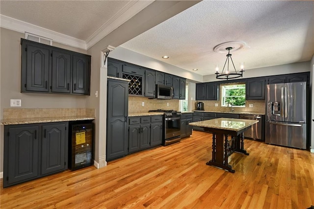 8 Apache Dr, Lake Winnebago, MO 64034 - kitchen with stainless steel appliances, beverage cooler, a textured ceiling, a chandelier, and light wood-style flooring