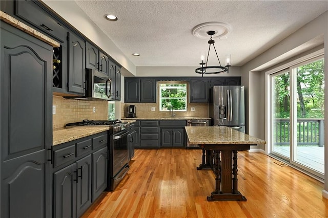 8 Apache Dr, Lake Winnebago, MO 64034 - kitchen with stainless steel appliances, a textured ceiling, backsplash, light wood-style floors, and light stone counters