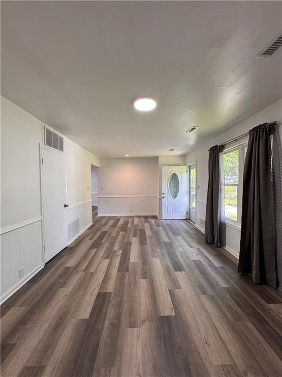 7703 E 107th St, Kansas City, MO 64134 - unfurnished living room with dark wood-style flooring, a wainscoted wall, a decorative wall, and baseboards