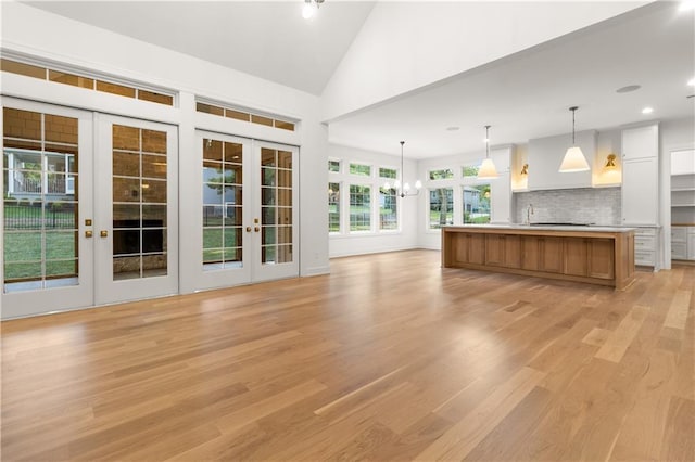 18568 W 180th Ct, Olathe, KS 66062 - unfurnished living room with light wood-style flooring, french doors, a chandelier, vaulted ceiling, and recessed lighting