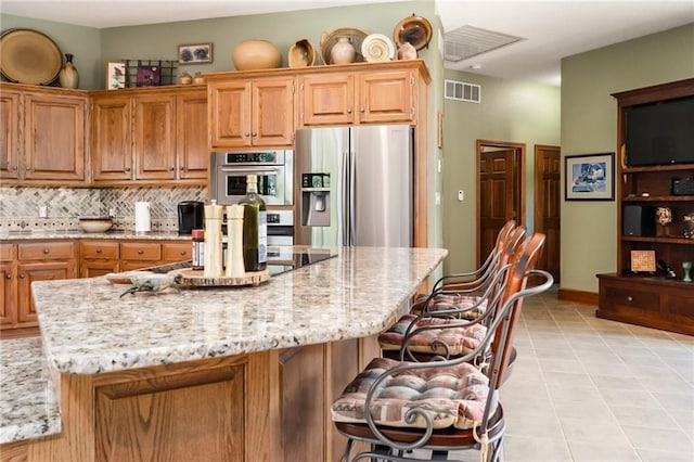 1672 N 1st Rd, Baldwin City, KS 66006 - kitchen with appliances with stainless steel finishes, light stone countertops, a breakfast bar, a kitchen island, and tasteful backsplash