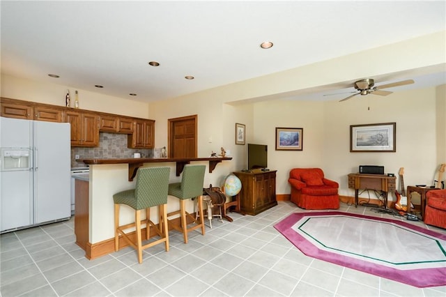 1672 N 1st Rd, Baldwin City, KS 66006 - kitchen with white fridge with ice dispenser, a breakfast bar, brown cabinets, open floor plan, and a ceiling fan