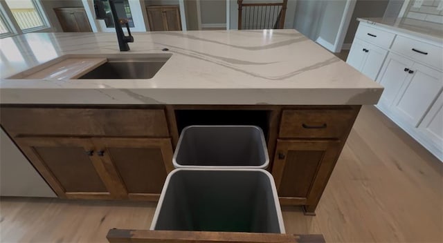 19079 Millstone Ter, Saint Joseph, MO 64505 - kitchen with light stone counters, light wood-style flooring, a sink, white cabinets, and an island with sink