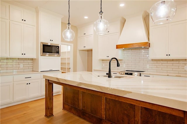 19079 Millstone Ter, Saint Joseph, MO 64505 - kitchen featuring custom exhaust hood, stainless steel microwave, a sink, light stone counters, and white cabinetry