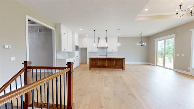19079 Millstone Ter, Saint Joseph, MO 64505 - kitchen with a chandelier, backsplash, light wood-style floors, white cabinetry, and recessed lighting