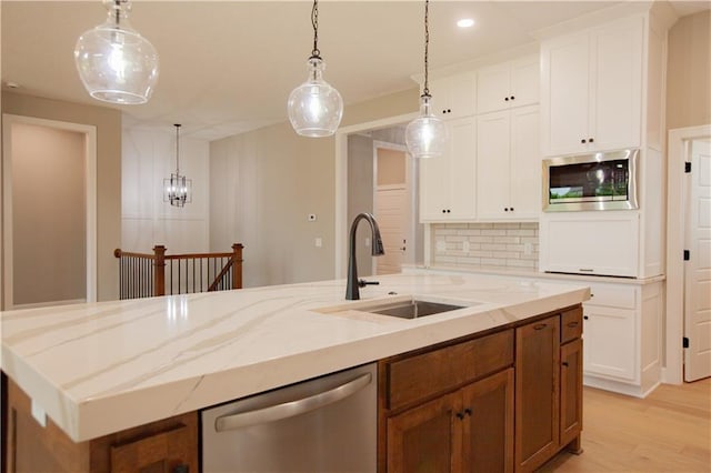 19079 Millstone Ter, Saint Joseph, MO 64505 - kitchen with appliances with stainless steel finishes, a sink, a kitchen island with sink, light wood finished floors, and decorative backsplash