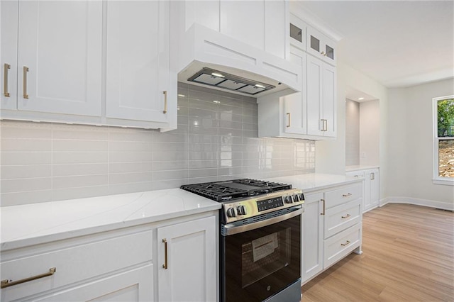 6932 Kenton St, Shawnee, KS 66226 - kitchen with stainless steel gas range oven, white cabinetry, light stone countertops, backsplash, and light wood-type flooring