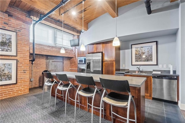 712 Broadway Blvd Unit 607, Kansas City, MO 64105 - kitchen with stainless steel appliances, brick wall, brown cabinetry, a sink, and a breakfast bar