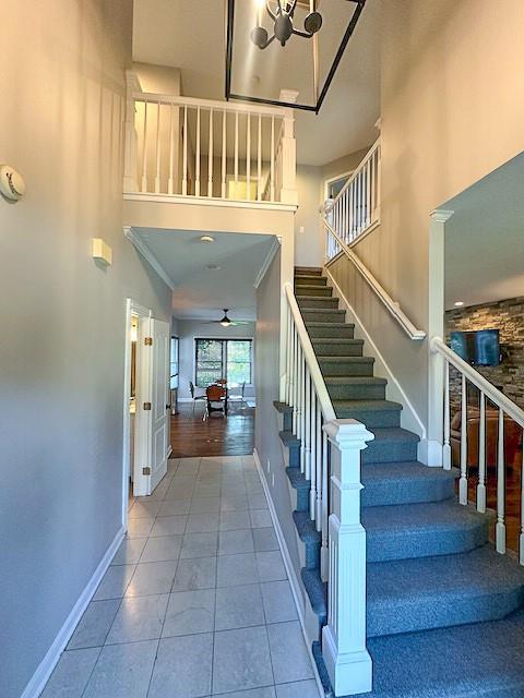1101 SW Sunflower Dr, Lees Summit, MO 64081 - staircase featuring a towering ceiling, baseboards, tile patterned flooring, and ceiling fan