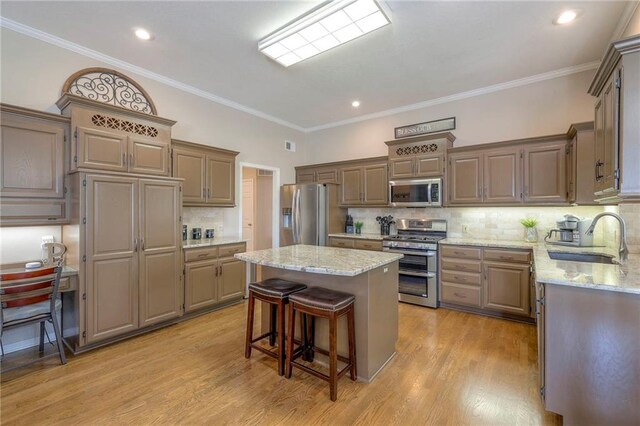 7904 W 153rd Ter, Overland Park, KS 66223 - kitchen featuring stainless steel appliances, a kitchen island, tasteful backsplash, light wood-style floors, and crown molding