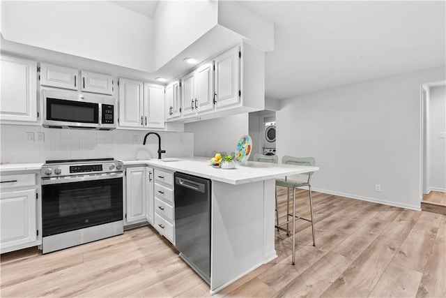 44 G St, Lake Lotawana, MO 64086 - kitchen featuring stainless steel appliances, a sink, stacked washer / dryer, light countertops, and white cabinets
