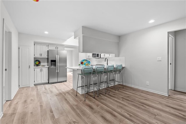 44 G St, Lake Lotawana, MO 64086 - kitchen with stainless steel refrigerator with ice dispenser, light wood finished floors, a peninsula, light countertops, and recessed lighting
