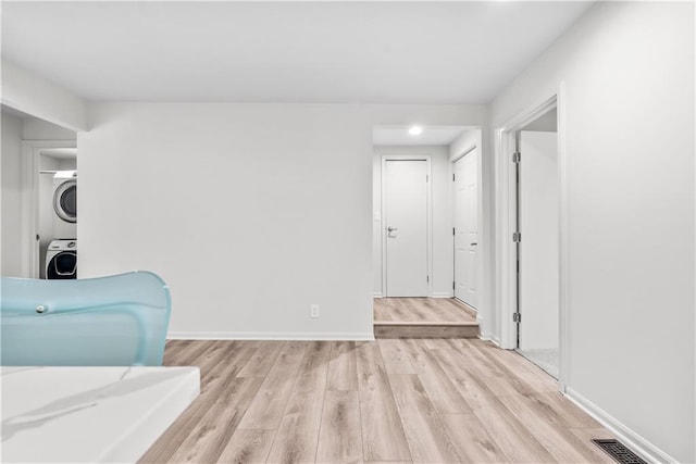 44 G St, Lake Lotawana, MO 64086 - living area featuring stacked washing machine and dryer, light wood-style floors, and baseboards
