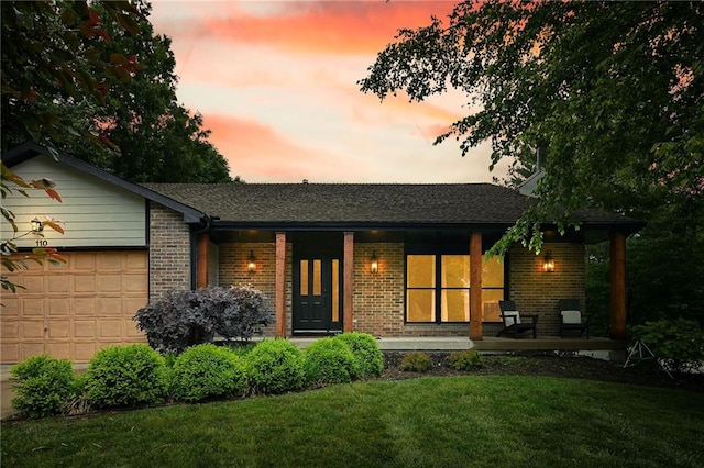 110 Cherokee Ln, Lake Winnebago, MO 64034 - back of house at dusk with a porch, an attached garage, a lawn, and brick siding