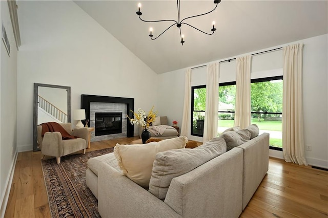 110 Cherokee Ln, Lake Winnebago, MO 64034 - living room featuring high vaulted ceiling, light wood-style flooring, a chandelier, baseboards, and a glass covered fireplace