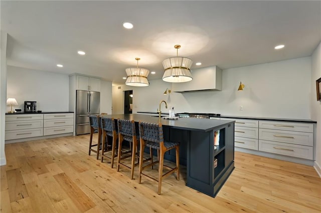 110 Cherokee Ln, Lake Winnebago, MO 64034 - kitchen with freestanding refrigerator, dark countertops, a sink, light wood-style floors, and a kitchen breakfast bar