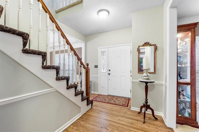 12806 Goddard Ave, Overland Park, KS 66213 - foyer entrance with stairway, light wood-type flooring, baseboards, and a textured ceiling