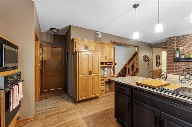 12806 Goddard Ave, Overland Park, KS 66213 - kitchen featuring oven, light wood-style floors, stainless steel microwave, hanging light fixtures, and light countertops