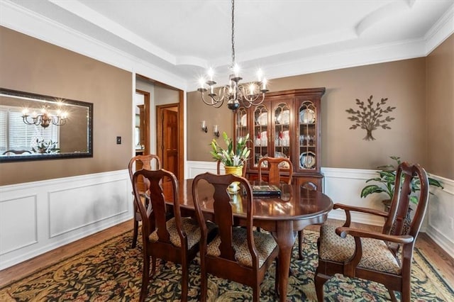 12806 Goddard Ave, Overland Park, KS 66213 - dining area with a chandelier, wood finished floors, a tray ceiling, a wainscoted wall, and crown molding