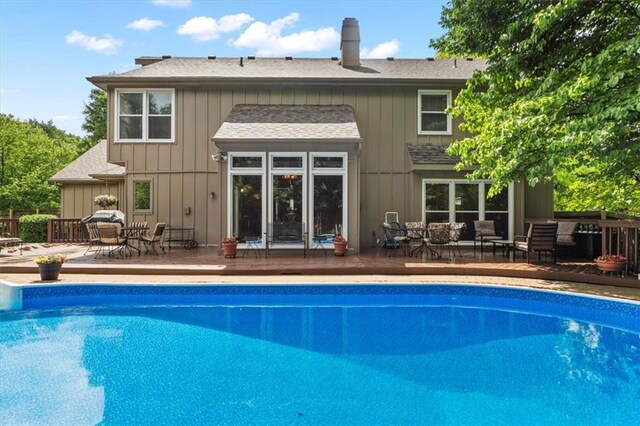 12806 Goddard Ave, Overland Park, KS 66213 - rear view of property with an outdoor pool, a shingled roof, board and batten siding, and an outdoor living space