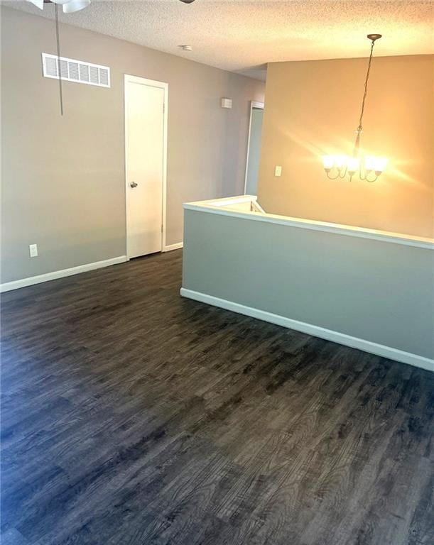 10636 N Grand Ave, Kansas City, MO 64155 - empty room featuring dark wood-type flooring, a textured ceiling, baseboards, and a chandelier