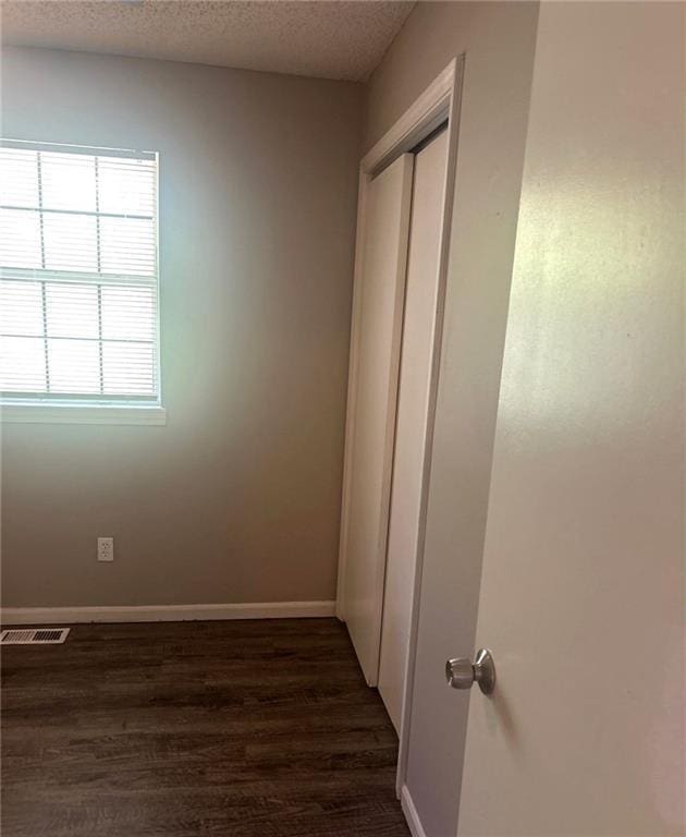 10636 N Grand Ave, Kansas City, MO 64155 - unfurnished bedroom featuring dark wood-style floors, a textured ceiling, baseboards, and a closet
