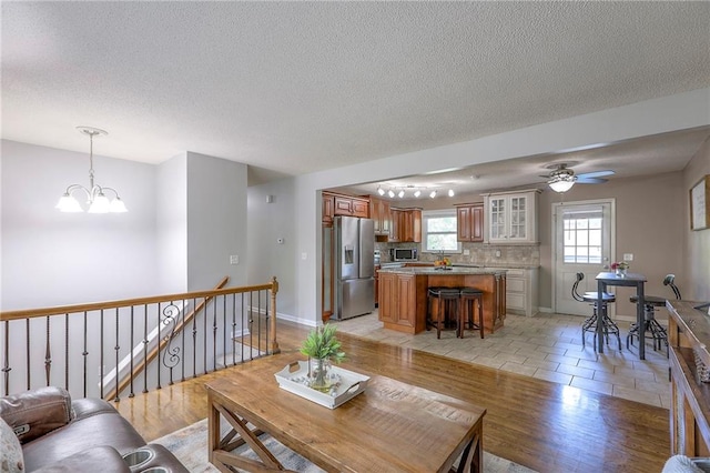 606 W Smith St, Spring Hill, KS 66083 - living room featuring a chandelier, a textured ceiling, a ceiling fan, and light wood finished floors