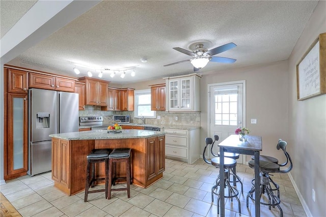 606 W Smith St, Spring Hill, KS 66083 - kitchen featuring appliances with stainless steel finishes, plenty of natural light, a kitchen breakfast bar, a center island, and a textured ceiling