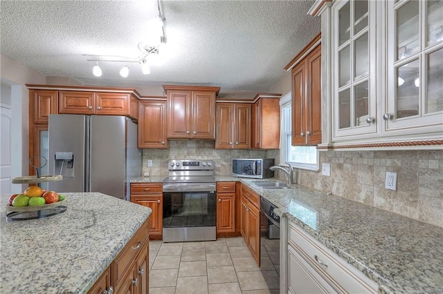 606 W Smith St, Spring Hill, KS 66083 - kitchen with stainless steel appliances, brown cabinetry, a textured ceiling, light stone countertops, and backsplash