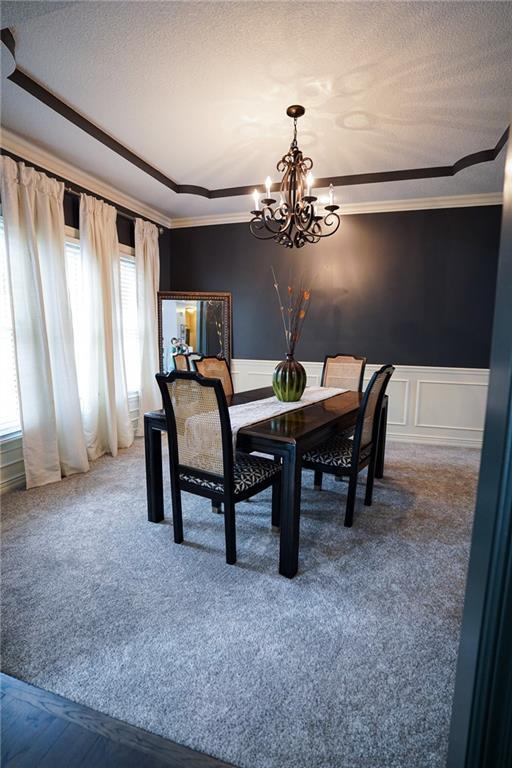 3832 SW Boulder Dr, Lees Summit, MO 64082 - dining space featuring a chandelier, ornamental molding, carpet flooring, wainscoting, and a decorative wall