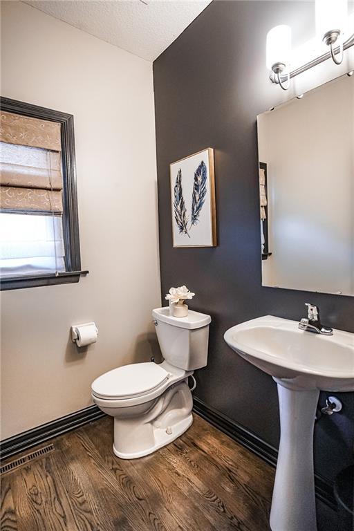 3832 SW Boulder Dr, Lees Summit, MO 64082 - bathroom featuring toilet, wood finished floors, baseboards, and a textured ceiling
