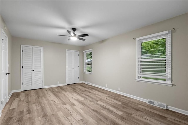 8632 Larsen St, Overland Park, KS 66214 - unfurnished bedroom with multiple windows, light wood-style flooring, multiple closets, and baseboards