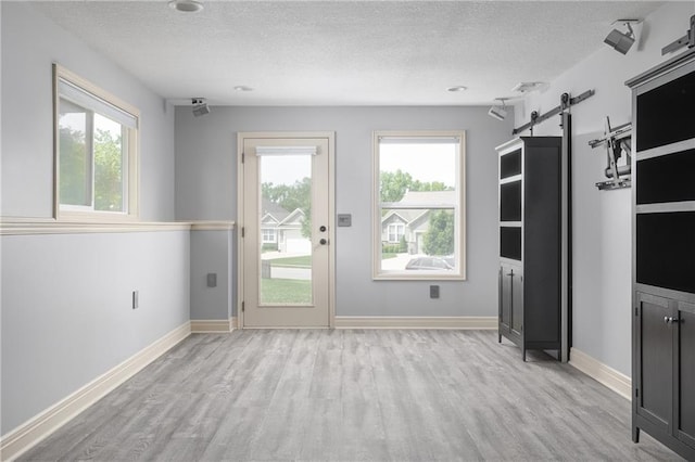 486 S 137th Pl, Bonner Springs, KS 66012 - entryway featuring a barn door, light wood-type flooring, a textured ceiling, plenty of natural light, and baseboards