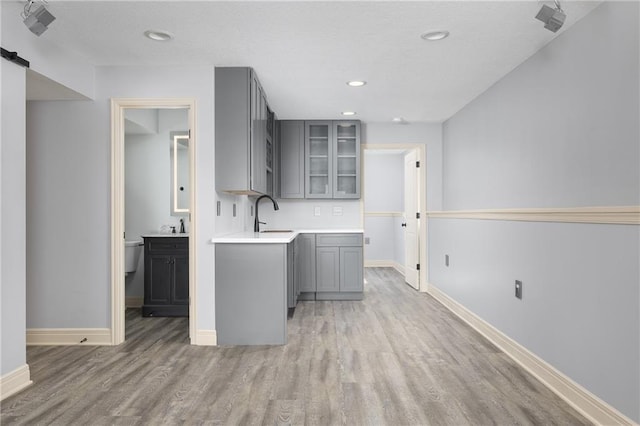 486 S 137th Pl, Bonner Springs, KS 66012 - kitchen with gray cabinetry, light wood-type flooring, glass insert cabinets, light countertops, and baseboards
