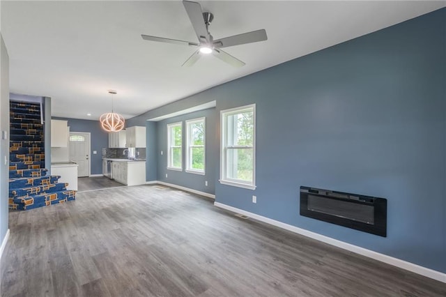 4233 Euclid Ave, Kansas City, MO 64130 - unfurnished living room with dark wood-type flooring, baseboards, and ceiling fan