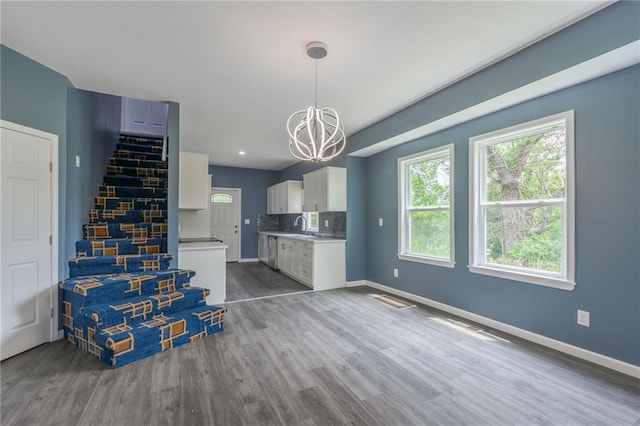 4233 Euclid Ave, Kansas City, MO 64130 - kitchen with white cabinets, a chandelier, light countertops, wood finished floors, and baseboards