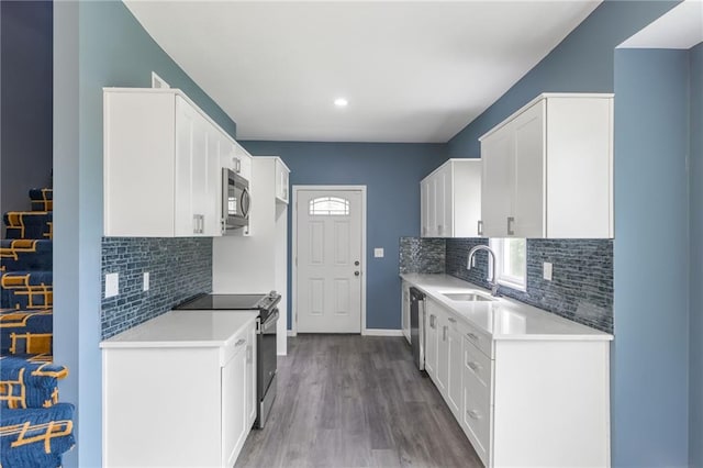4233 Euclid Ave, Kansas City, MO 64130 - kitchen featuring stainless steel appliances, a sink, wood finished floors, white cabinets, and recessed lighting
