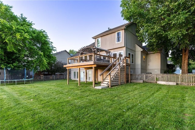 5916 NE Turquoise Dr, Lees Summit, MO 64064 - back of property featuring stairs, a trampoline, and a wooden deck