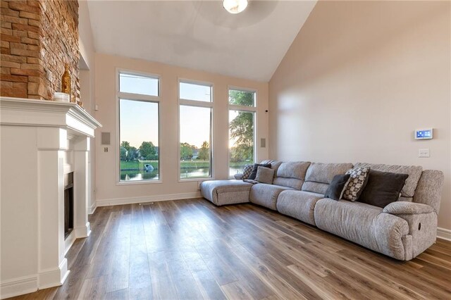 5916 NE Turquoise Dr, Lees Summit, MO 64064 - living area featuring high vaulted ceiling, a fireplace, wood finished floors, and baseboards