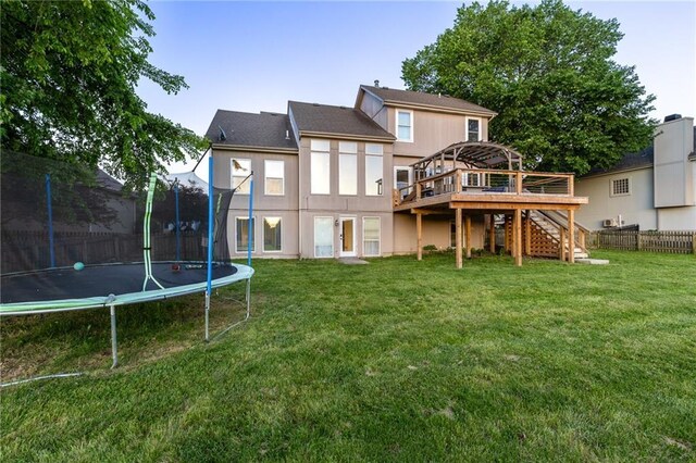 5916 NE Turquoise Dr, Lees Summit, MO 64064 - back of house with a trampoline, stairway, a deck, and stucco siding