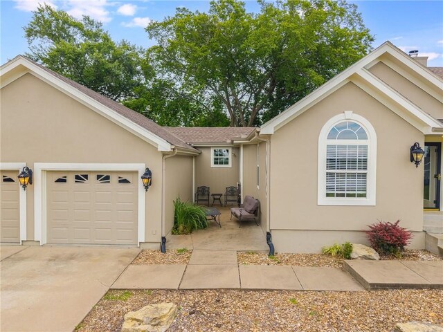 1955 Birmingham Rd, Liberty, MO 64068 - view of front of house with driveway, a garage, and stucco siding