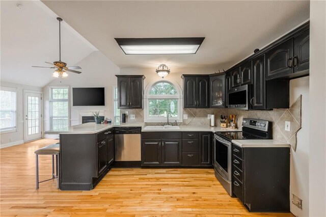1955 Birmingham Rd, Liberty, MO 64068 - kitchen with appliances with stainless steel finishes, a peninsula, a ceiling fan, a kitchen breakfast bar, and light wood-type flooring