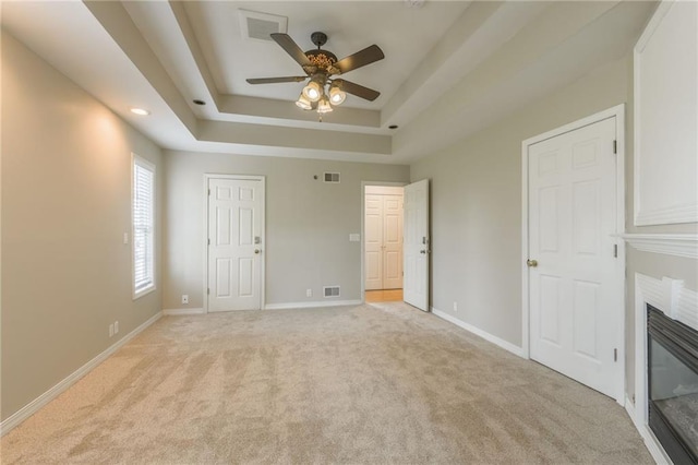 1955 Birmingham Rd, Liberty, MO 64068 - unfurnished bedroom featuring light colored carpet, a glass covered fireplace, a raised ceiling, recessed lighting, and ceiling fan